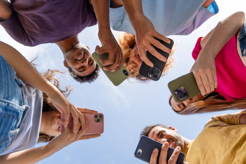 multiethnic group of friends taking selfie with smartphones